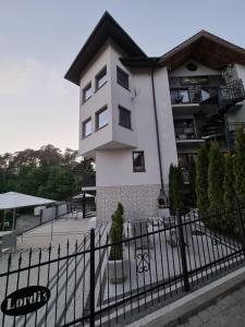 a white building with a black fence in front of it at Villa Lordis in Krynica Morska