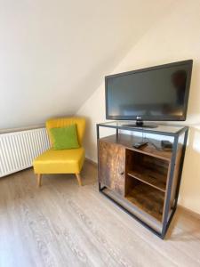 sala de estar con TV y silla amarilla en Pension / Ferienwohnungen Scheid, en Kestert