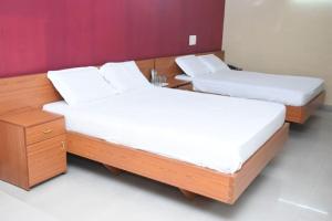 two beds in a room with white sheets and a table at Hotel Surya Residency Majestic in Bangalore