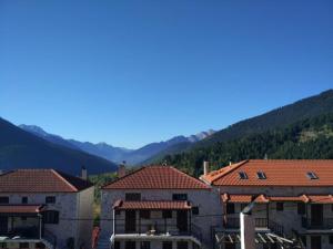 un groupe de bâtiments avec des montagnes en arrière-plan dans l'établissement La Casa di Pietra, à Karpenísi