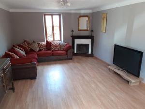 a living room with a red couch and a flat screen tv at Chambre d'hôtes de puy faucher in Arrènes