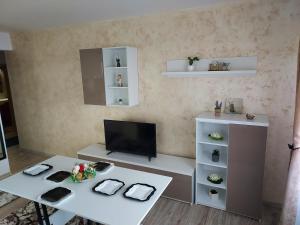 a living room with a white table and a tv at Mona in Mamaia