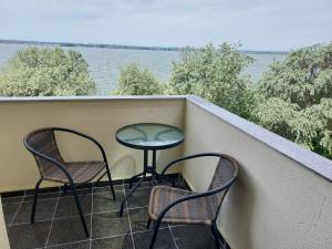two chairs and a table on a balcony overlooking the water at Mona in Mamaia