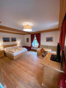 a large bedroom with a large bed and a desk at Ristorante Rifugio Ospitale in Cortina dʼAmpezzo