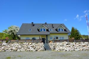 a house with a fence and a stone wall at Apartamenty i Pokoje Gościnne Ala in Szklarska Poręba