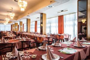 a dining room filled with tables with red table linens at Hotel San Pietro in Cesenatico