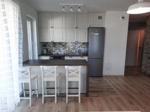 a kitchen with a counter with stools and a refrigerator at Apartament za świerkami in Kołobrzeg