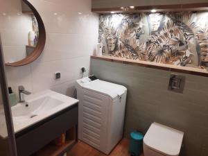 a bathroom with a sink and a toilet and a mirror at Apartament za świerkami in Kołobrzeg