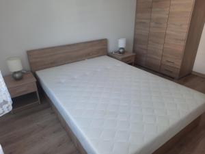 a large bed in a room with two night stands at Apartament za świerkami in Kołobrzeg