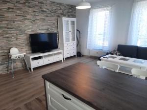 a living room with a flat screen tv on a brick wall at Apartament za świerkami in Kołobrzeg