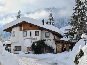 un hombre parado en el techo de una casa cubierta de nieve en Camping Gasthof Zirknitzer, en Großkirchheim