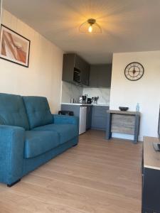 a living room with a blue couch and a kitchen at Appartement en bord de Mer in Sète