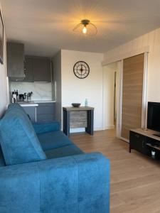 a living room with a blue couch and a kitchen at Appartement en bord de Mer in Sète