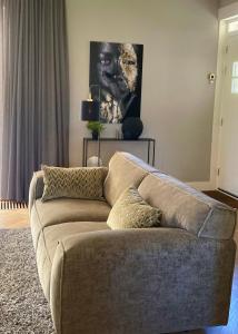 un sofá marrón en una sala de estar con una pintura en Hoeve Altena Apartment, en Woudrichem