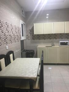 cocina con mesa, fregadero y encimera en كريستال الذهبية en Taif