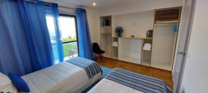 1 dormitorio con 1 cama con cortinas azules y ventana en HOME4U en Horta