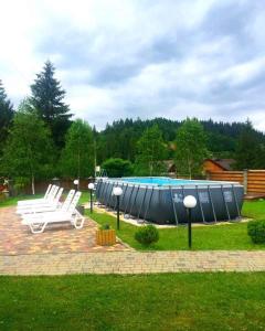 - une piscine avec deux chaises blanches et un radeau bleu dans l'établissement Karpatskyi Maetok, à Slavsko