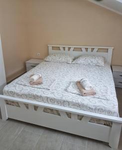Una cama blanca con dos pares de zapatillas. en Apartmani Popović V&A, en Tivat