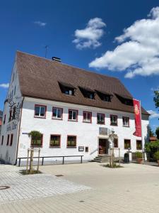 un grand bâtiment blanc avec un toit marron dans l'établissement Gasthof - Pension - Adler, à Weiler-Simmerberg