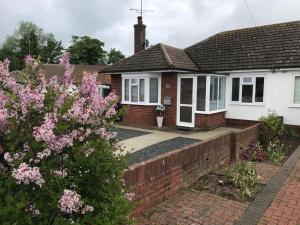 a house with a brick driveway and pink flowers at Oyster Beach Cottage in Whitstable