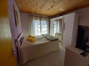 1 dormitorio con 1 cama y ventana con TV en marias, en Campos do Jordão