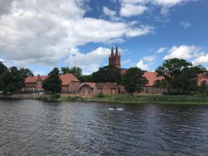 a person in a boat on a river with a church at Großer Familien-Wohnwagen - Keine Bauarbeiter-Unterkunft! in Dobbertin