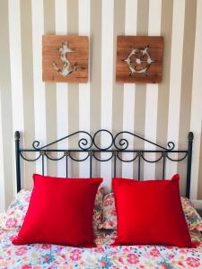 a bed with two red pillows and a striped wall at Apartamento El Capricho in Cudillero