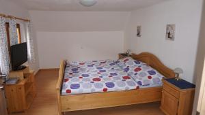 een slaapkamer met een bed met een dekbed en een televisie bij Haus Cilli in Donnersbachwald