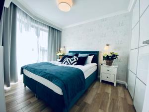 a bedroom with a blue bed and a window at SeaHome Horyzont z parkingiem in Międzyzdroje