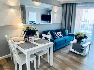 a living room with a table and a blue couch at SeaHome Horyzont z parkingiem in Międzyzdroje