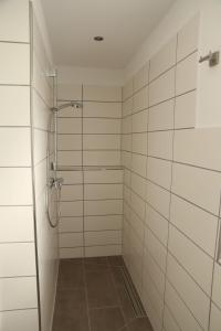 a bathroom with a shower with white tiles at Ferienwohnung Evi in Walkenried
