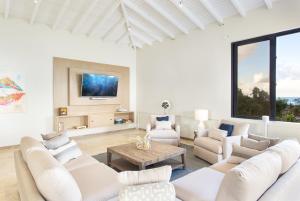 a living room with white furniture and a flat screen tv at Sandcastle Beach House in The Valley