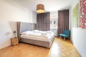 sypialnia z łóżkiem i niebieskim krzesłem w obiekcie Naschmarkt Premium Apartment in "Your Vienna" w Wiedniu