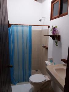 baño con aseo y cortina de ducha azul en Posada Hondumar Holbox en Holbox Island