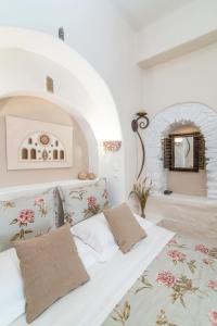 a white room with a bed with pillows at Madalena's Family Rooms in Tinos Town