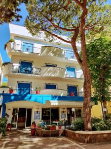 un edificio con un árbol delante de él en Hotel Adria B&B - Colazione fino alle 12, en Misano Adriatico