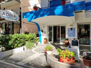 a store with a blue awning and potted plants on a sidewalk at Hotel Adria B&B - Colazione fino alle 12 in Misano Adriatico