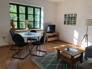 a living room with a table and chairs and a tv at Villenappartement mit Blick ins Grüne am Rande der wunderschönen Altstadt in Wismar