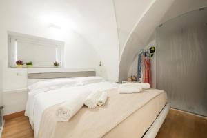 Un dormitorio blanco con una cama con toallas. en Palestro 5, en Leverano