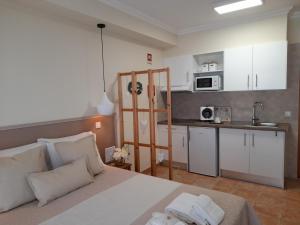 a bedroom with a white bed and a kitchen at Cantinho do Burgau in Burgau