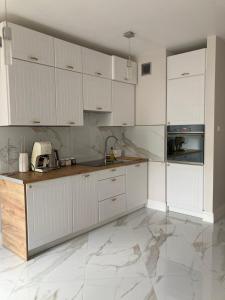 a kitchen with white cabinets and a marble floor at Apartment Kaczorowskiego 14 in Białystok