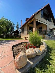 a garden in front of a house with rocks and flowers at Villa Katerina in Nea Kallikrateia