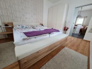 ein weißes Bett in einem Zimmer mit Holzboden in der Unterkunft Haus Julia in Großkirchheim