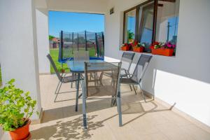 a glass table and chairs on a patio with plants at Family House Pristol in Pristol