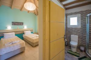 a room with two beds and a bathroom with a toilet at Villas Porto Kamini Afionas Corfu in Afionas +25 photos