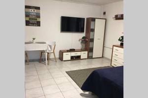 een woonkamer met een tafel en een tv aan de muur bij JAndi apartman in Hévíz