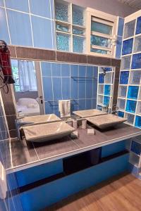 a blue tiled bathroom with two sinks and a mirror at SOLEIL COUCHANT - Gîtes in Deshaies