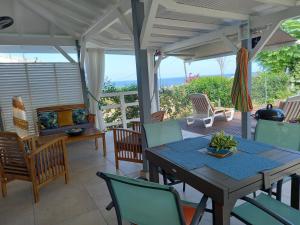 una mesa y sillas en un porche con vistas al océano en Les Gites Capra - Villa Aiméandre piscine et Spa, en Bouillante