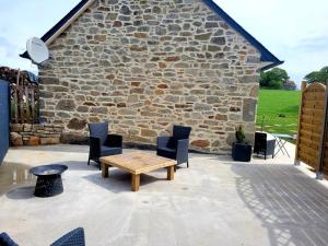 een patio met stoelen, een tafel en een stenen muur bij Ti Mein Glas, maison proche de Quimper in Landudal