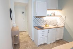 una cucina con armadi bianchi e lavandino di Mageiras Boutique Hotel ad Áfitos Altre 37 foto